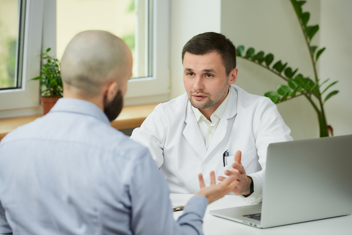 Doctor explaining testosterone replacement therapy to male patient representing the difference between TRT and steroids